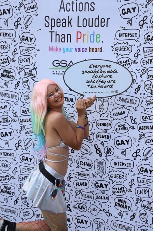 Community members at a Pride event holding hand-lettered speech-bubble signs